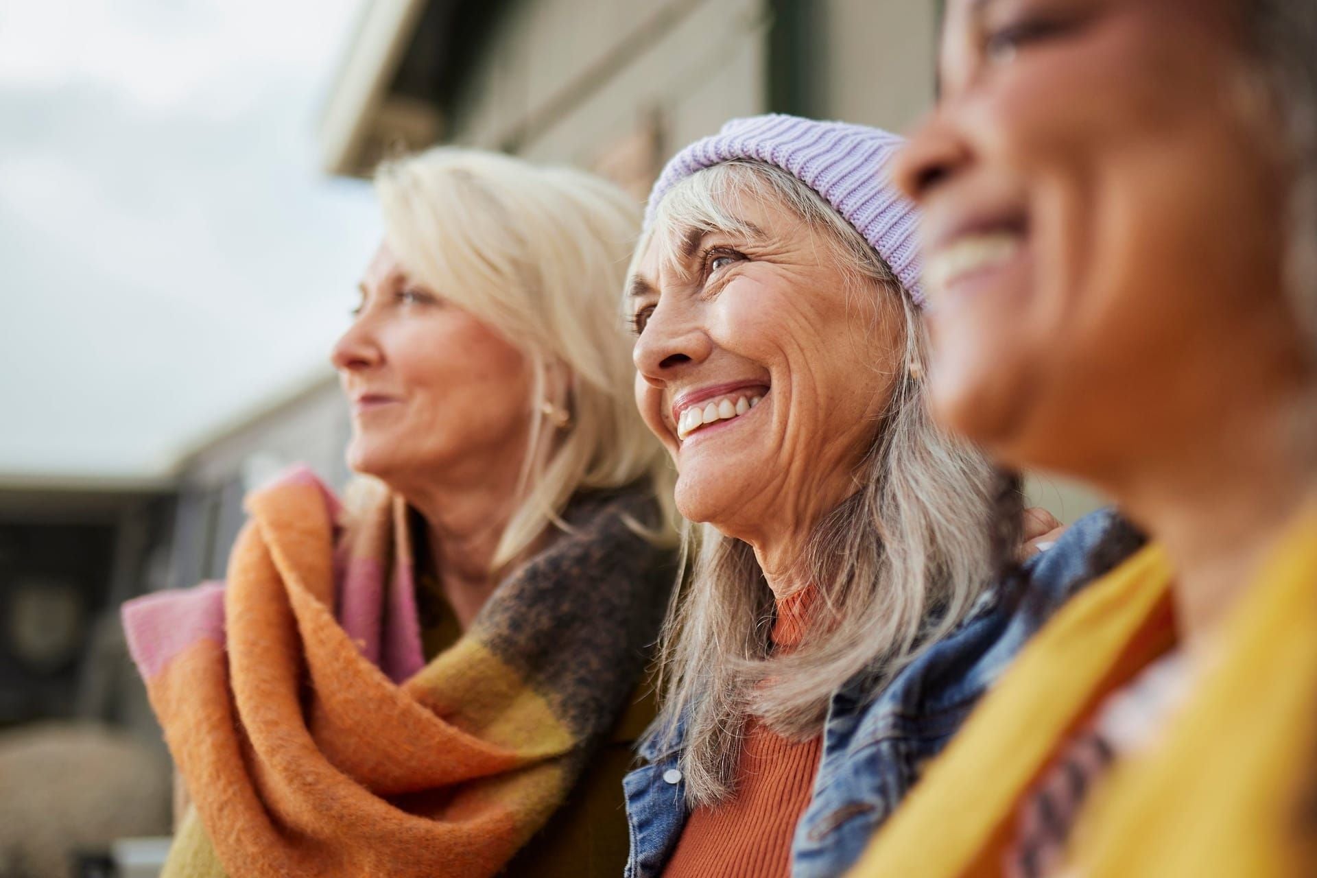 Three women smiling outdoors together.